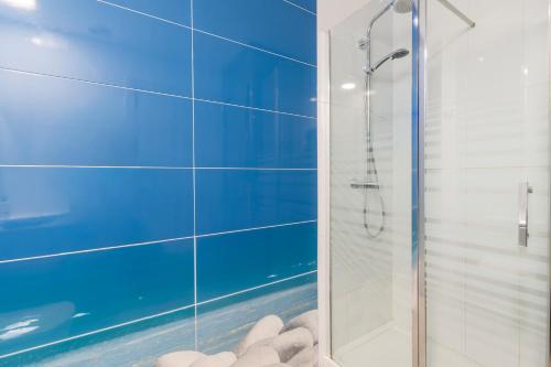 baño con ducha de cristal con azulejos azules en Cuentame, en Alcudia