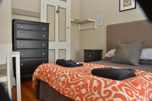 a bedroom with a bed with an orange and white blanket at Royal Gatton Hotel in Gatton