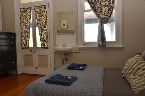 1 dormitorio con cama, lavabo y ventanas en Royal Gatton Hotel, en Gatton