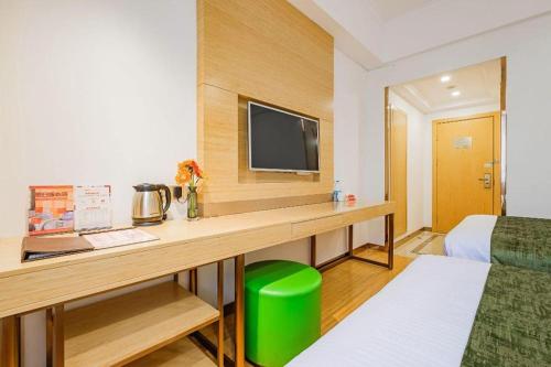 a hotel room with a desk with a tv at GreenTree Inn Shanghai Jingan Railway Station Xinzha Road Business Hotel in Shanghai