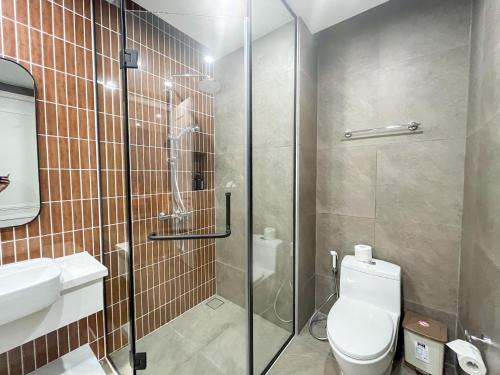 a bathroom with a toilet and a glass shower at Sunset town Phú Quốc in Phu Quoc