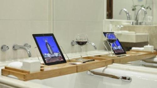 a bathroom with two tablet computers and a glass of wine at New Century Grand Hotel Zhuji Yaojiang in Shaoxing