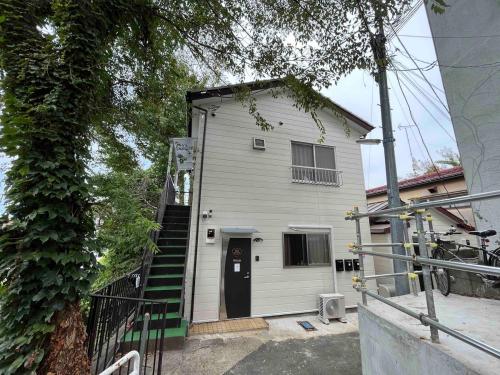 a white house with a black door and stairs at Sweet house 101 東武練馬101 in Tokyo