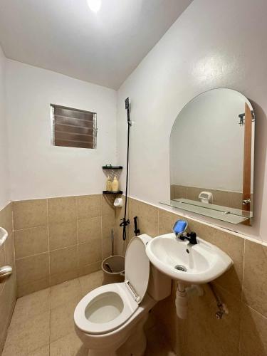 a bathroom with a toilet and a sink and a mirror at Maria Staycation House in Davao City