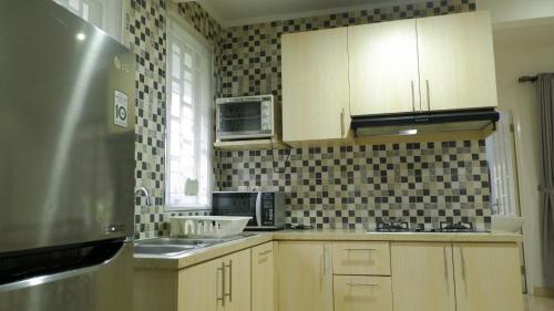 a kitchen with wooden cabinets and a stainless steel refrigerator at Diyar Villas Puncak M6-11 in Puncak