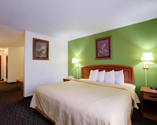 a hotel room with a large bed with green walls at Quality Inn & Suites Airport in Austin