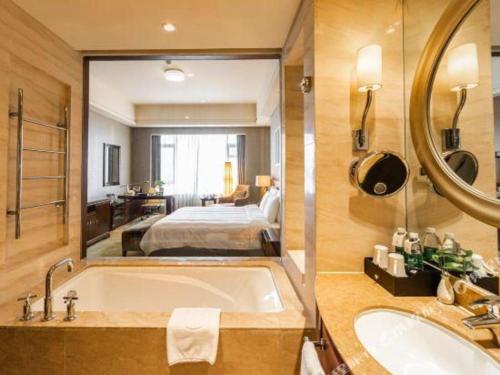 a bathroom with a bath tub and a bedroom at Quanzhou Guest House Hotel in Quanzhou