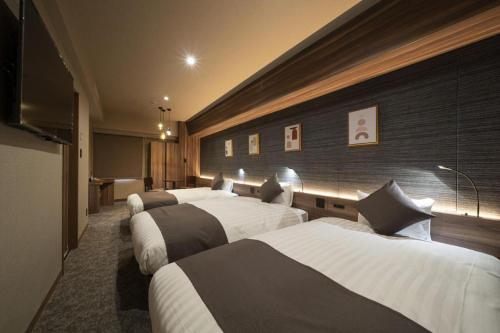 a row of four beds in a hotel room at Nagoya B's Hotel in Nagoya