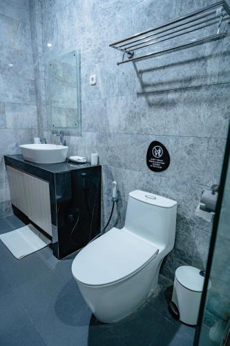a bathroom with a white toilet and a sink at INEZ Homestay in Timuran