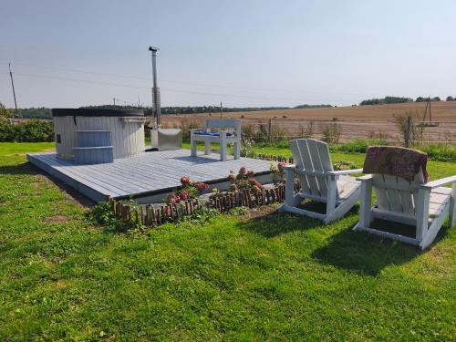 two chairs and a deck with flowers in the grass at Apartamenty Folwark Malinowy Chruśniak in Bisztynek