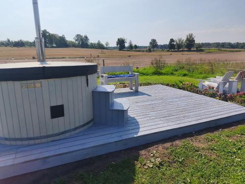 a wooden deck with a bench and a table at Apartamenty Folwark Malinowy Chruśniak in Bisztynek