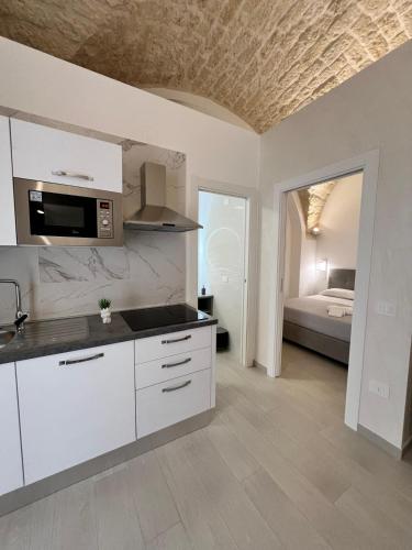 a kitchen with white cabinets and a room with a bed at Cuore di casa in Manfredonia