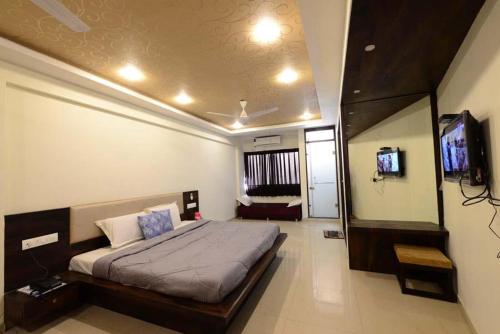 ein Schlafzimmer mit einem Bett und einem Flachbildfernseher in der Unterkunft Hotel Manila in Ahmedabad