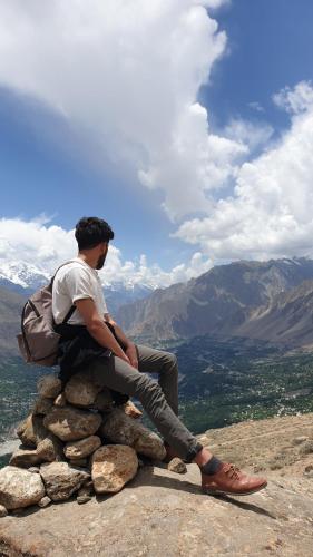 a man sitting on a pile of rocks on a mountain at Rakaposhi Base Camp Site in Minapin