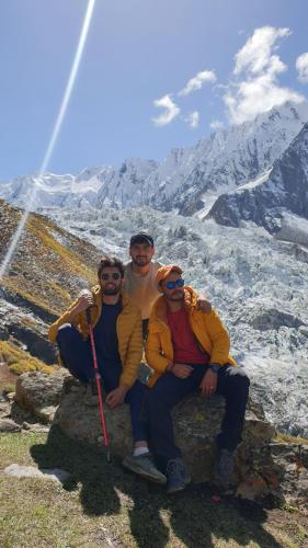 three people sitting on a rock on a mountain at Rakaposhi Base Camp Site in Minapin