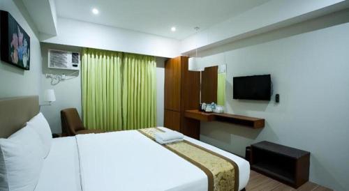 a hotel room with a bed and a television at Hotel Fleur de Liz in Panglao
