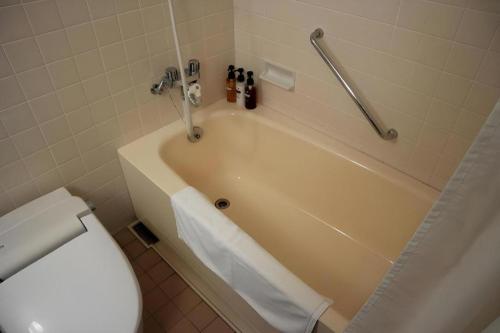 a bathroom with a toilet and a bath tub at Grand Hotel New Oji in Tomakomai