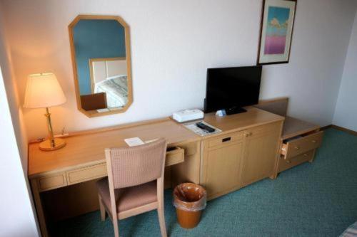a room with a desk with a computer and a mirror at Grand Hotel New Oji in Tomakomai