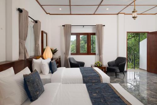 a hotel room with a bed and two chairs at Mirage Kandyan Heights in Kandy