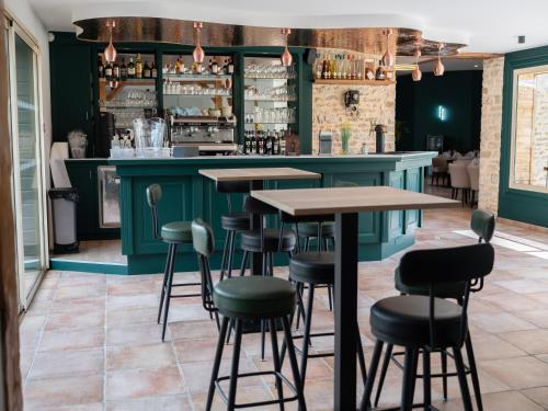 a bar with green walls and tables and chairs at Logis Hôtel-Restaurant Domaine de Montecristo in Bourguignons