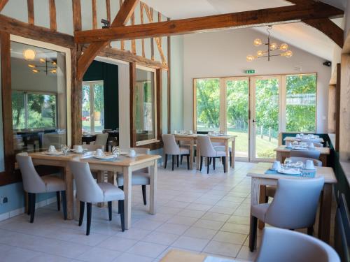 a dining room with tables and chairs and windows at Logis Hôtel-Restaurant Domaine de Montecristo in Bourguignons