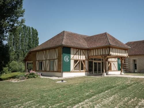 a house with a gambrel roof and a yard at Logis Hôtel-Restaurant Domaine de Montecristo in Bourguignons