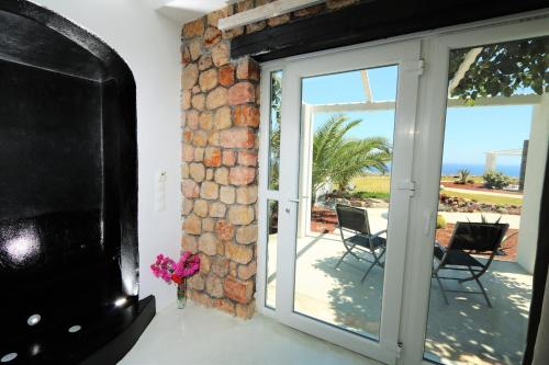 a living room with a stone wall and a sliding glass door at Thea Luxury Resort in Fira