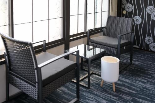 two chairs and a table in a room with windows at グッドタイム細越 in Aomori