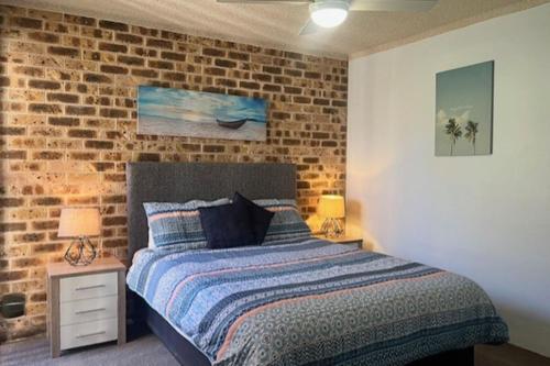 a bedroom with a bed and a brick wall at Bay Parklands 23 located at Little Beach with air con pool and tennis court in Shoal Bay