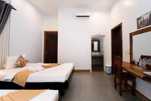 a bedroom with a bed and a desk and a mirror at Sanna Suite Villa in Siem Reap