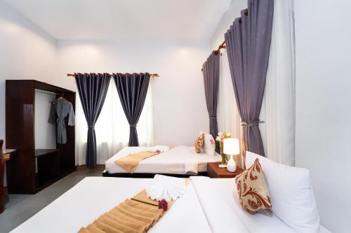 a hotel room with two beds and curtains at Sanna Suite Villa in Siem Reap