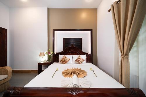 a bedroom with a large bed with a wooden headboard at Sanna Suite Villa in Siem Reap