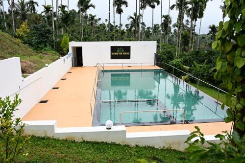 a swimming pool with a wooden deck and a building at Wayanad Farm Heritage in Sultan Bathery