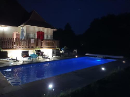 a swimming pool at night in front of a house at Cocon de charme in La Chapelle-Gonaguet