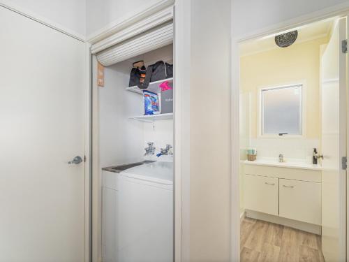 un bagno bianco con lavandino e specchio di Beverley Beach - Whangamata Holiday Home a Whangamata