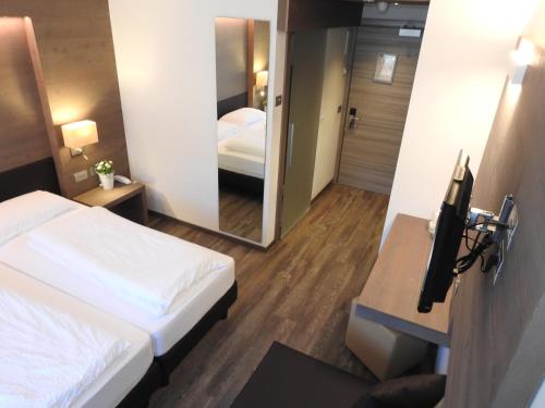 a hotel room with two beds and a mirror at Hotel Montana in Madonna di Campiglio