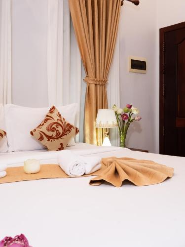 a white bed with a pillow and towels on it at Sanna Suite Villa in Siem Reap