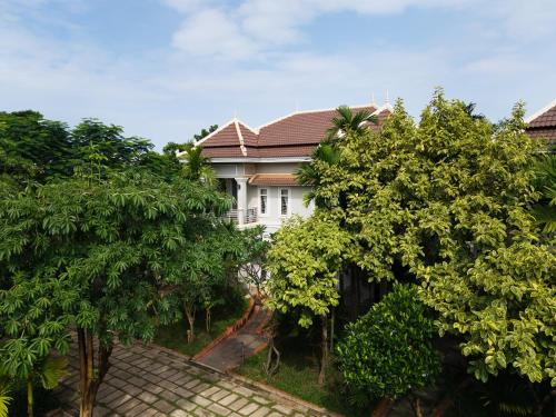 a white house with trees in front of it at Sanna Suite Villa in Siem Reap