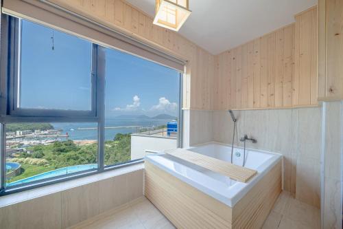 a bathroom with a tub and a large window at Brown Dote Hotel Geunpohang in Geoje 