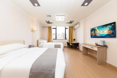ein Hotelzimmer mit zwei Betten und einem Schreibtisch in der Unterkunft Shiyi Business Hotel Pazhou-Free shuttle bus for canton fair in Guangzhou