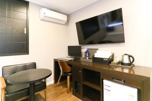 a room with a desk with a television and a table at Louis Hotel in Busan