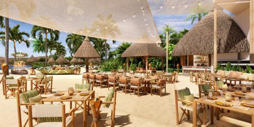 a restaurant with tables and chairs and straw umbrellas at Four Seasons Resort Mauritius at Anahita in Beau Champ