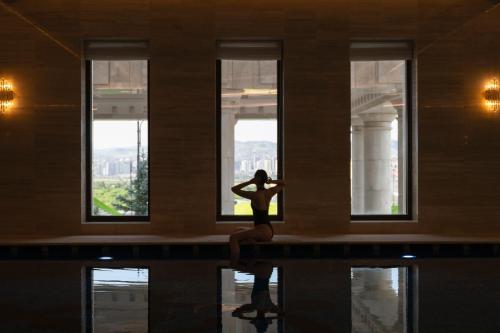 a woman sitting on a ledge in a room with windows at Ayan Zalaat in Ulaanbaatar