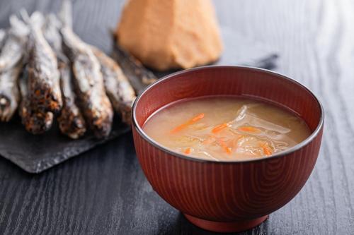 a red bowl of soup with carrots and other vegetables at Ooedo Onsen Monogatari Hotel Ranpu in Hirado