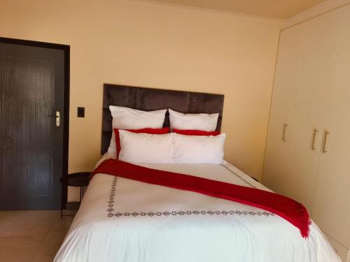 a bedroom with a large bed with red and white pillows at Masithandane lodge in Richards Bay
