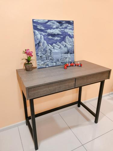 a wooden table with a painting and flowers on it at Onsen Premium Hotspring Suite Sunway Tambun Ipoh in Tambun