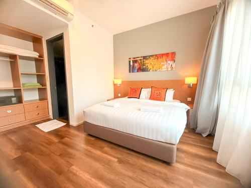 a bedroom with a large white bed and wooden floors at Onsen Premium Hotspring Suite Sunway Tambun Ipoh in Tambun