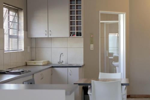 a kitchen with white cabinets and a table and chairs at Andela Guesthouse in Bloemfontein