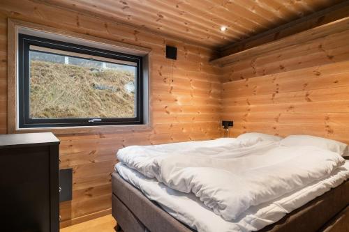 a bed in a wooden room with a window at Panoramahytte med fjellutsikt in Sogndal