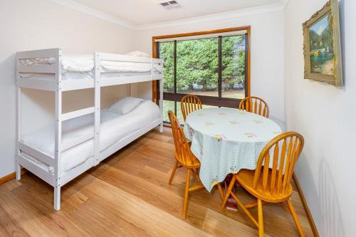 a dining room with a table and chairs and a bunk bed at Serene Farmhouse with Lake Views in Burrawang